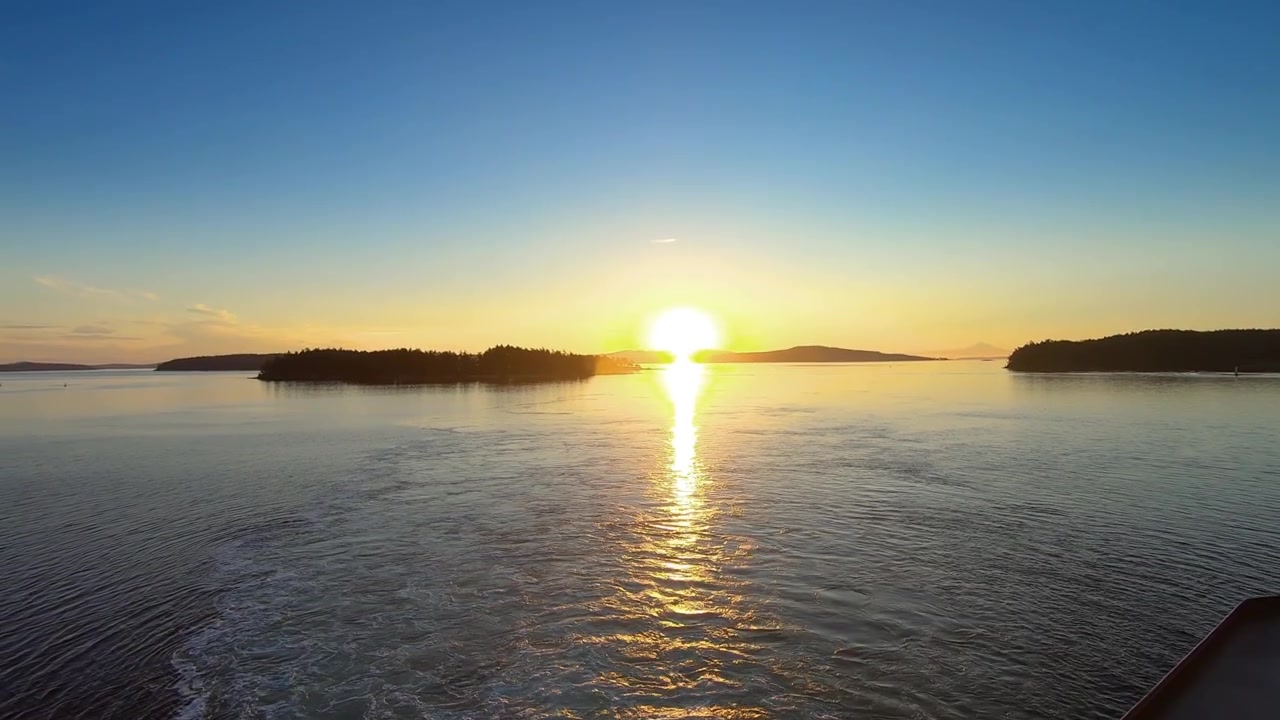 Wide angle of sunset view of sea horizon, small islands, and clear blue skies.