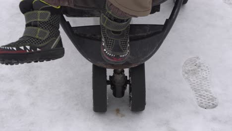 the feet of a young boy that is moving on a stroller