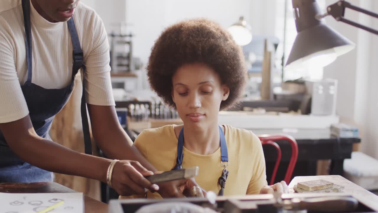 Busy diverse female workers shaping ring with handcraft tools in studio in slow motion