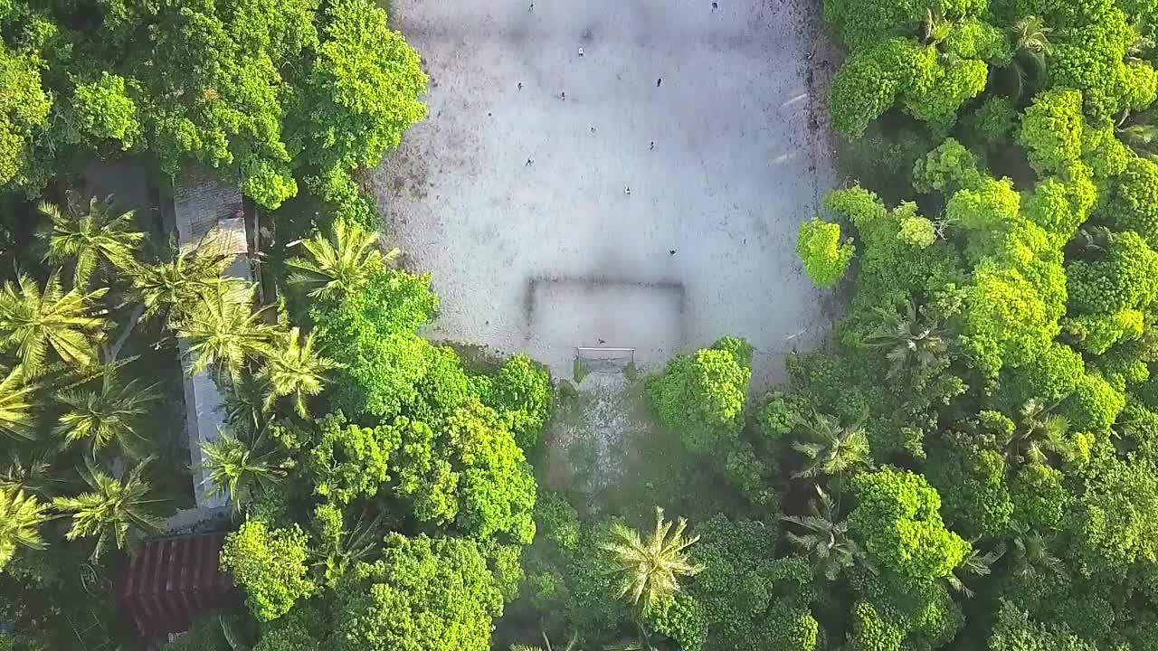 vuelo aéreo sobre el campo de fútbol y el bosque en la isla de malasia, toma completa avanzando en cámara lenta