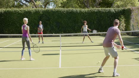 un grupo feliz y diverso de amigos jugando al tenis en la cancha de tenis