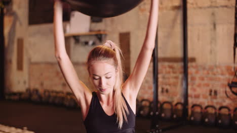 Confident-Young-Woman-Exercising-With-Fitness-Ball-At-Health-Club