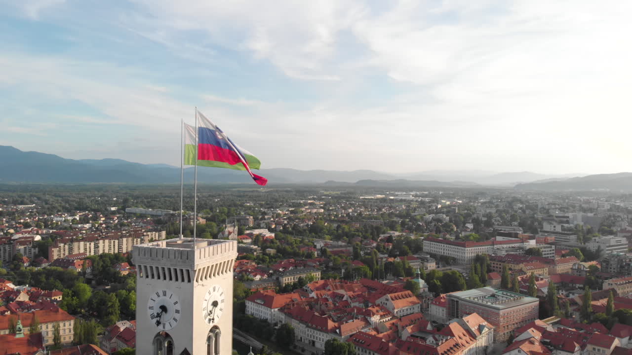 Ripresa drone di Lubiana e della bandiera della Slovenia in cima al Castello di Lubiana con vista sulla città e sulle colline retrostanti