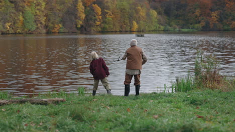 elderly couple fishing by a lake in autumn
