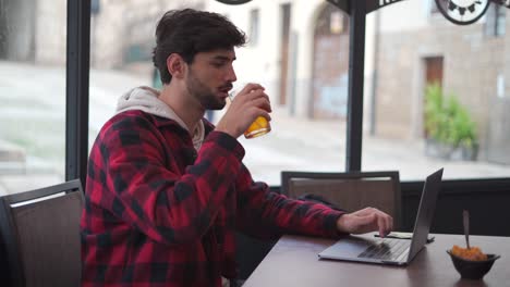 Man-drinking-a-soda-while-typing-on-a-laptop-compute