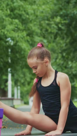 A Young Girl Practicing Stretching Techniques in a Lush Green Outdoor Setting, Demonstrating Flexibility and Concentration, Perfecting Her Skills Day by Day