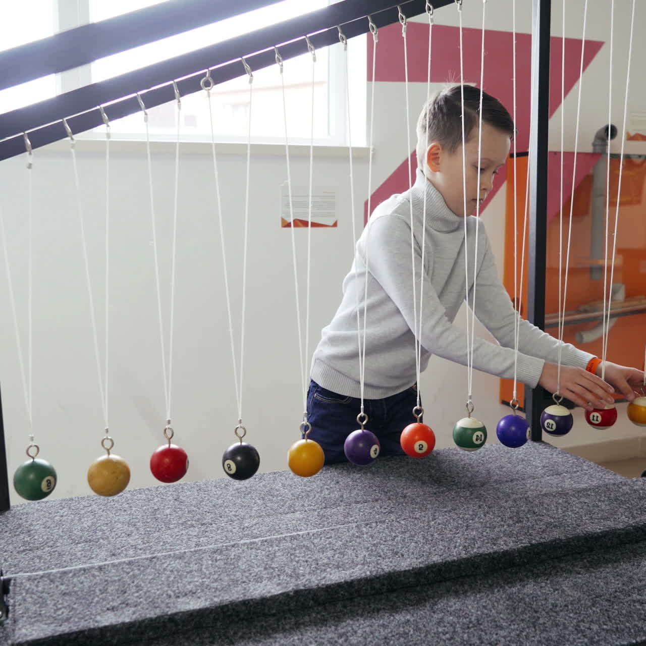 Boy makes an experiment with Newton's pendulum. The concept of physics. Museum of Science Square video