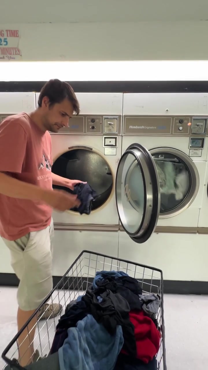 Man putting clothes into a dryer at a self service laundromat