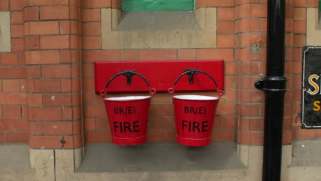 old red fire buckets at a vintage railway station