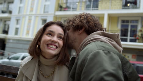 man whispering funny story to woman