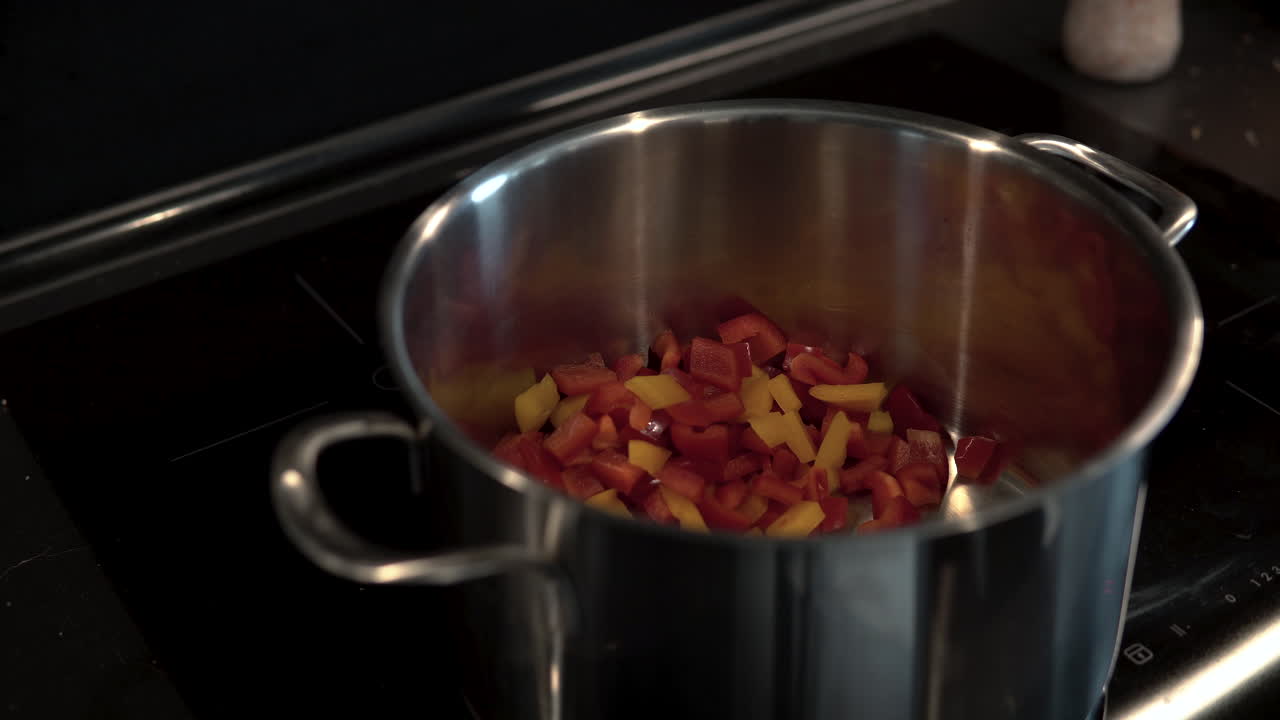 Pour chopped peppers, preparing vegetable meals, yellow and red chopped vegetables into the pot