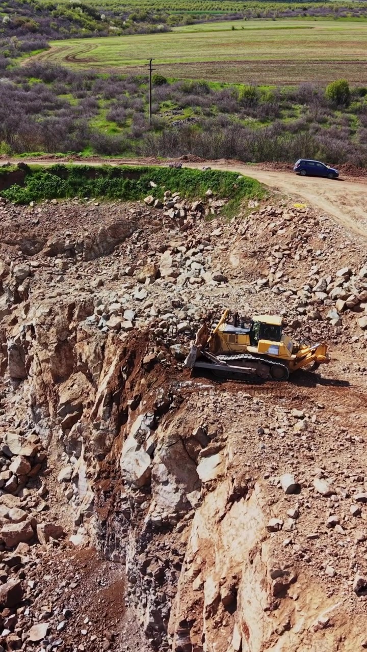 Construction work at a quarry with machinery digging in sunlight