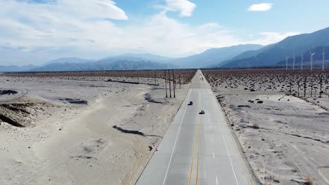 iconic usa desert highway with power lines and electric wind turbines, aerial low altitude view