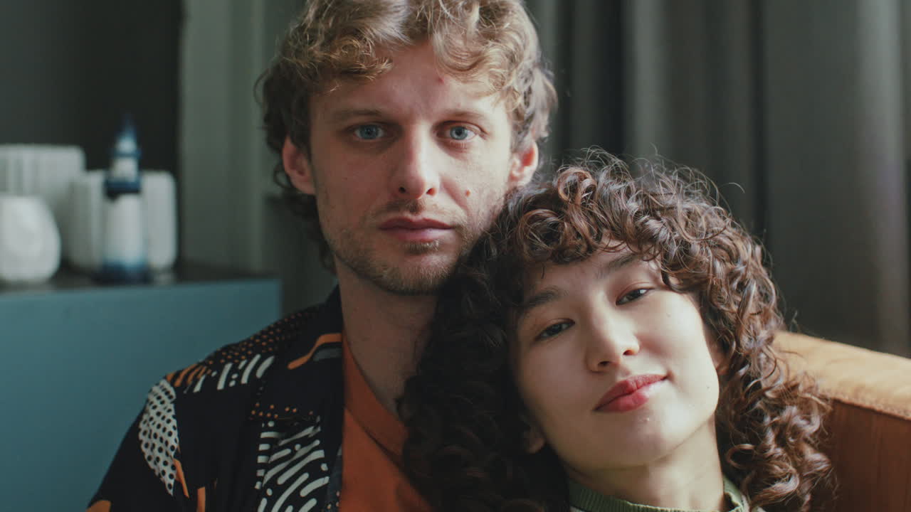 Portrait of Young Couple Sitting Close Together and Looking at Camera