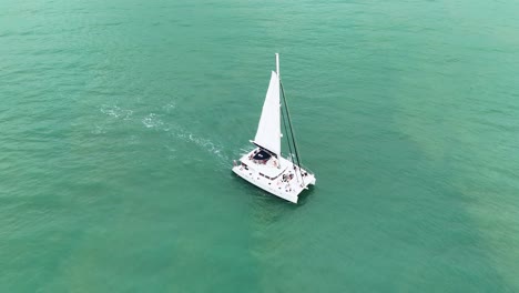 Drone captures a catamaran sailing smoothly over turquoise waters near Port Douglas, Queensland, under bright daylight