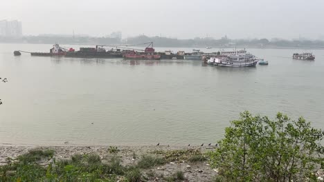 Profile-view-of-rows-of-ships-and-small-fishing-boats-piled-up-in-Hooghly-river-near-Babu-ghat-in-Kolkata,-India