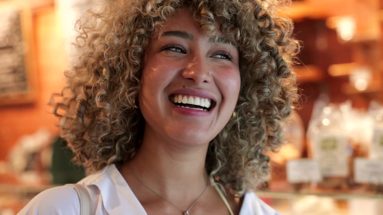 Jovem mulher tomando café e rindo em um café