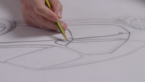 close up of male's hands drawing new car concept on a paper on the table in the studio