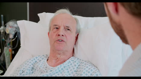 senior male patient and doctor talking in hospital room