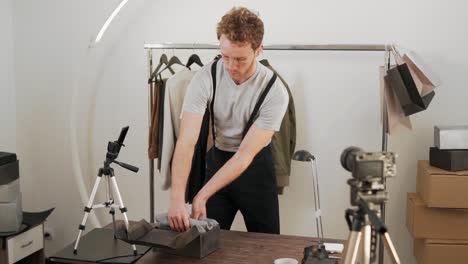 curly young guy packs a black cardboard box with gray tape