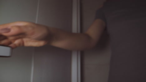 una mujer joven gira la perilla de metal para entrar en un pequeño baño