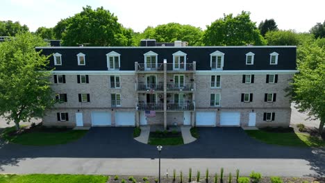 drone zooming in on an apartment complex with many units displaying the american flag