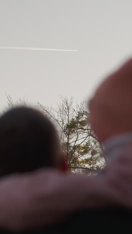 초록색 재을 입은 남자가 분홍색 재과 일치하는 베니를 입은 딸을 안고 둘 다 하늘을 쳐다보고 있습니다.