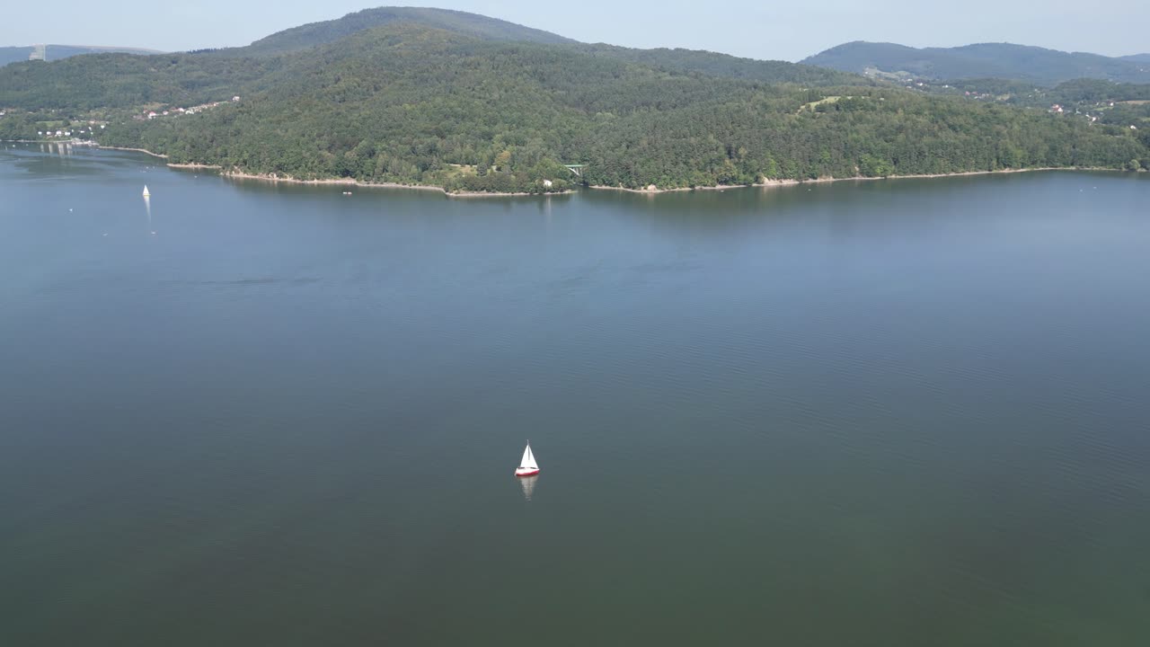lago sereno en las montañas beskid, rodeado de vegetación durante un día de verano - vista aérea 4k