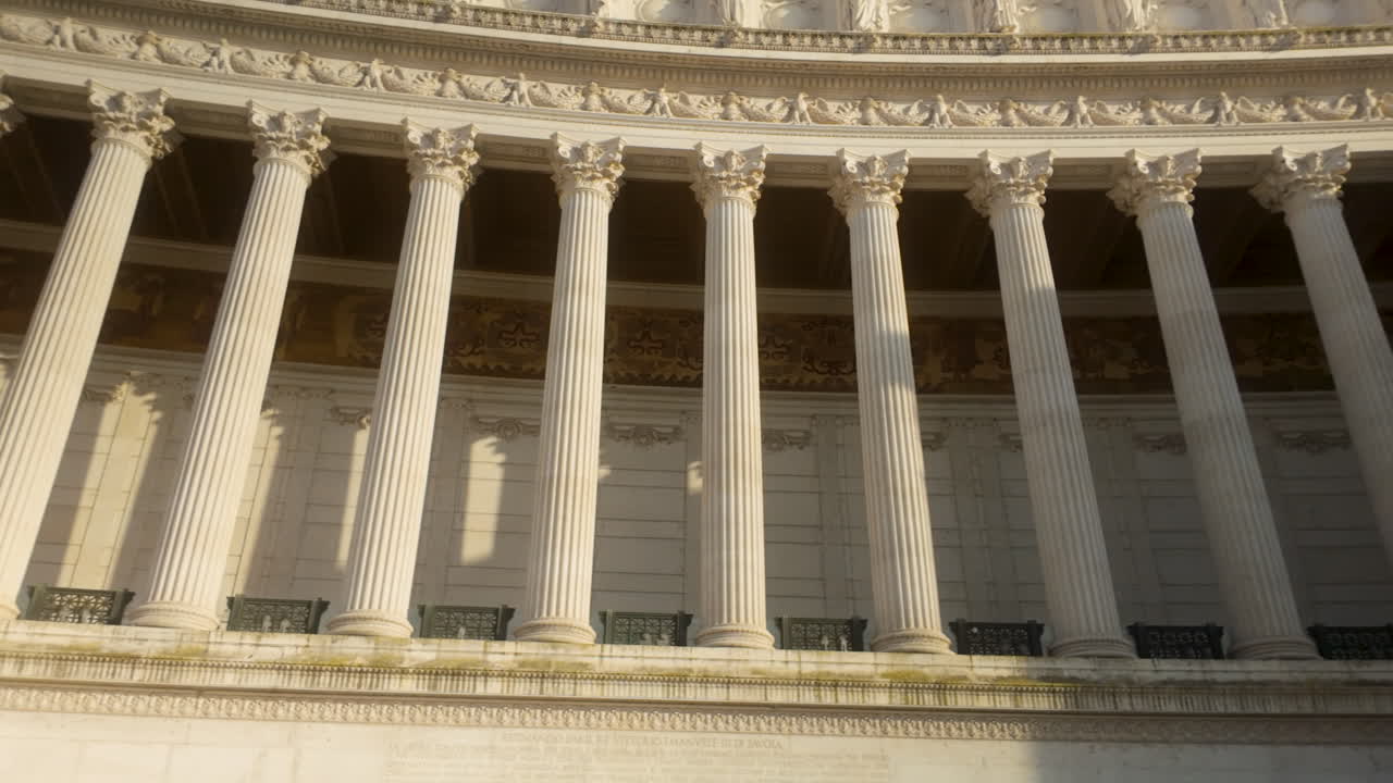 Close-up of neoclassical colonnade with Corinthian columns at Altare della Patria in Rome, glowing in warm sunlight.