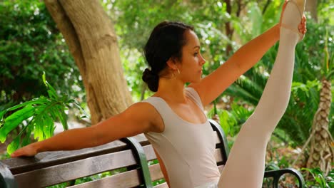 Beautiful-young-ballerina-doing-stretching-exercise-on-bench-in-the-park--4k