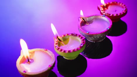 Close-up-of-burning-candles-in-row-celebrating-diwali-on-blue-background