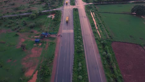 Luftaufnahme-Eines-Gütertransporters-Auf-Einer-Autobahn-Durch-Bauernhöfe-Im-Ländlichen-Gwalior-In-Indien-Während-Des-Sonnenuntergangs