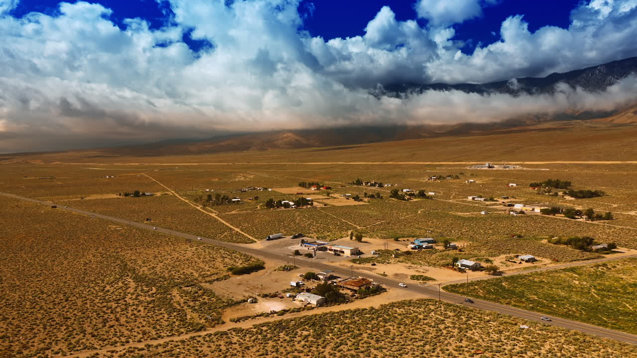 A little settlement located in the dry desert near the highway. White cloudscape covering the mountains at backdrop.
