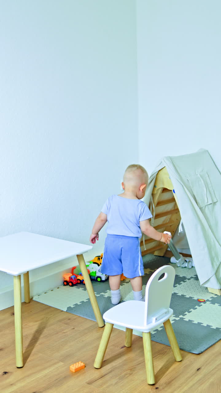 Child at home plays sitting on a rug. Children's room with toys for a child. Toddler boy plays and develops independently. Child's self-employment at home