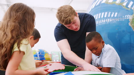 Gruppe-Von-Kindern-Macht-Puzzle-Mit-Lehrer-Im-Wissenschaftszentrum