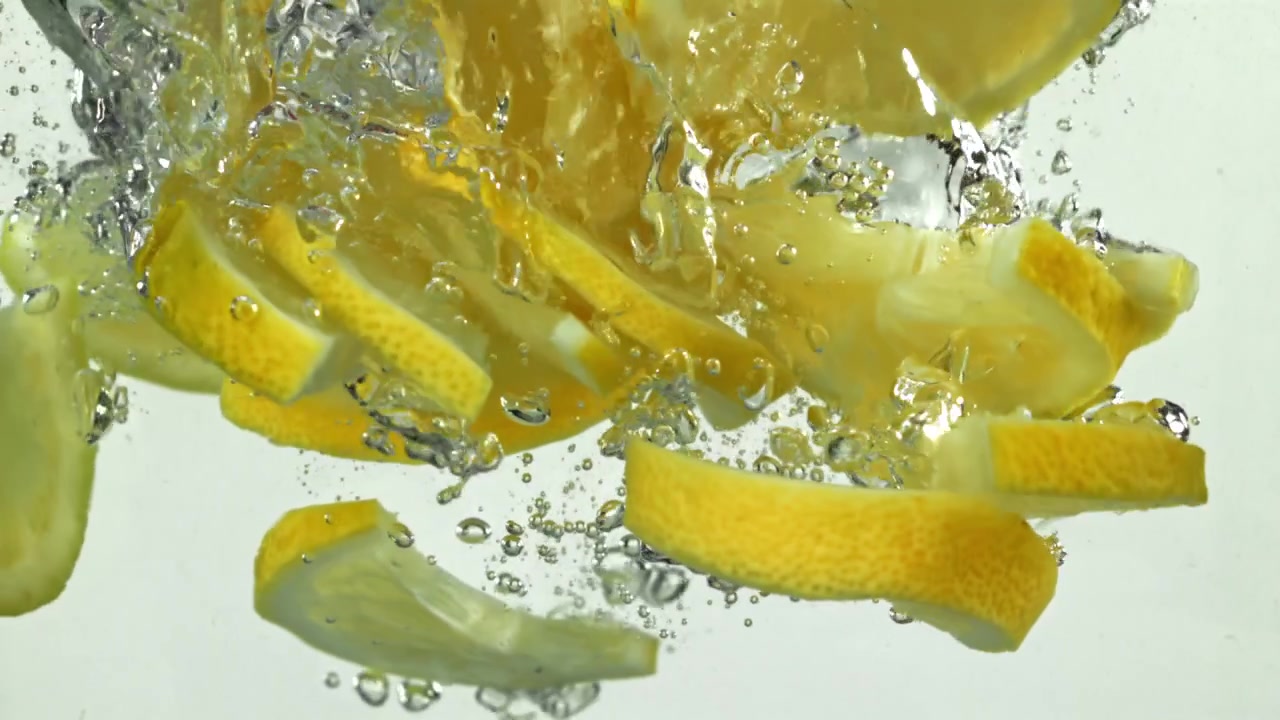 Slow Motion of Fresh Lemon Slices Dropping into Clear Water