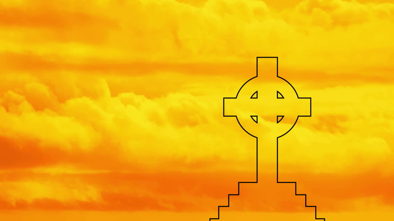 Silhouette of Celtic cross against vibrant orange and yellow cloudy sky