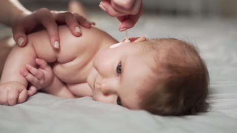 primer plano de manos femeninas limpiando las orejas del bebé con bastoncillos de algodón