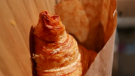 golden croissant in paper bag
