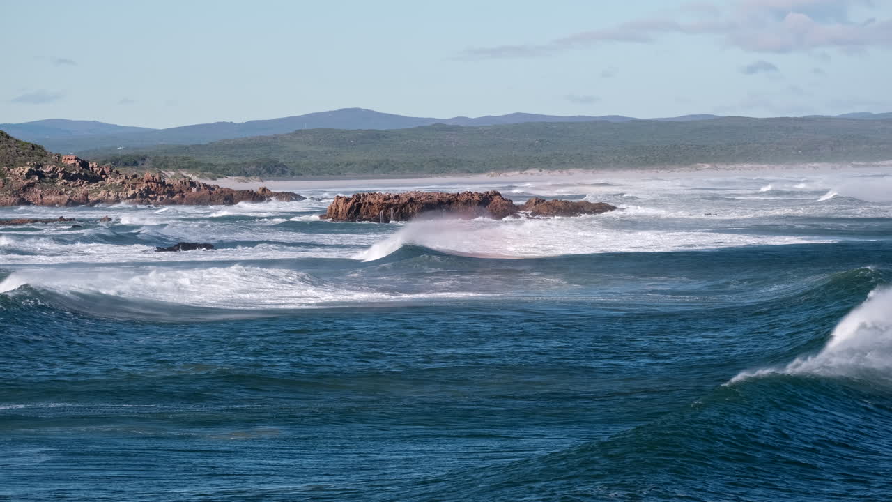 Powerful Atlantic swell surges toward coast with sea spray blown over crest