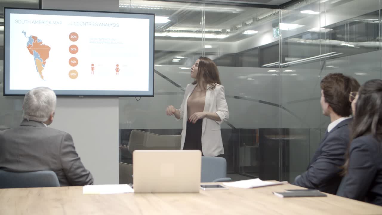 un joven orador confiado apuntando a la pantalla con gráficos