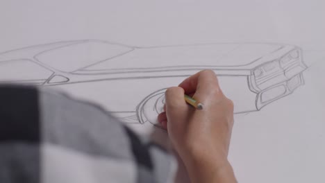 close up of male's hands drawing new car concept on a paper on the table in the studio