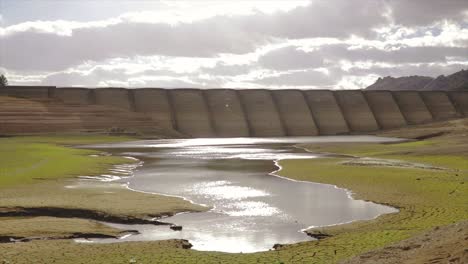 steady shot of a landscape of a dam and small lake with no water in it. global warming consequences.