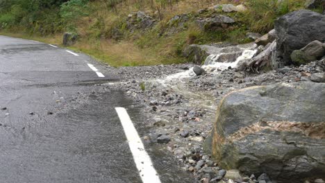 water flowing from hillside into road and over white road marking - closeup of water flowing over asphalt