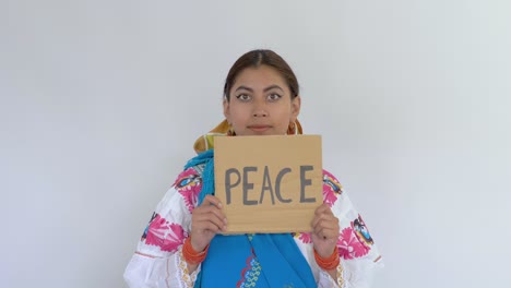 clip de una joven latina morena vestida con el traje tradicional de cayambe mostrando un mensaje que dice "paz"