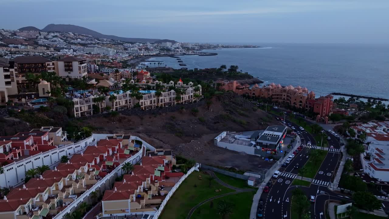 Vista aerea dei resort di Costa Adeje al crepuscolo mentre un drone scende delicatamente verso il mare