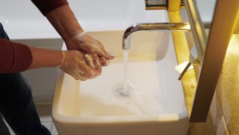 hotel guest washing hands with soap in the bathroom sink, tap water running through faucet