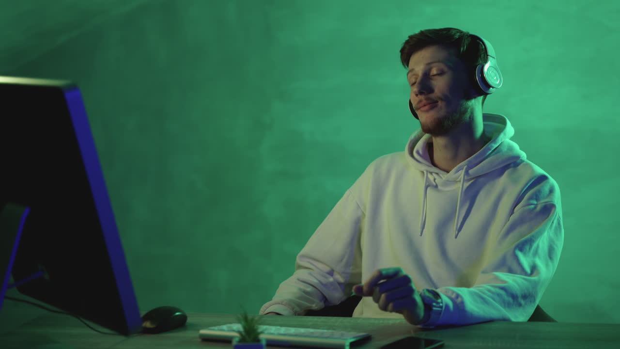 Young man working with a computer and wireless headphones on a colorful background