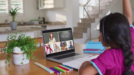 Schoolgirl-using-laptop-for-online-lesson-at-home,-with-diverse-teacher-and-class-on-screen