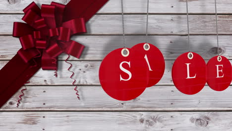 red sale tags hanging against wood with festive bow